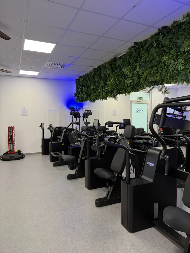 Moderne Technogym-Geräte für die Krankengymnastik am Gerät unter einer Pflanzenwand
